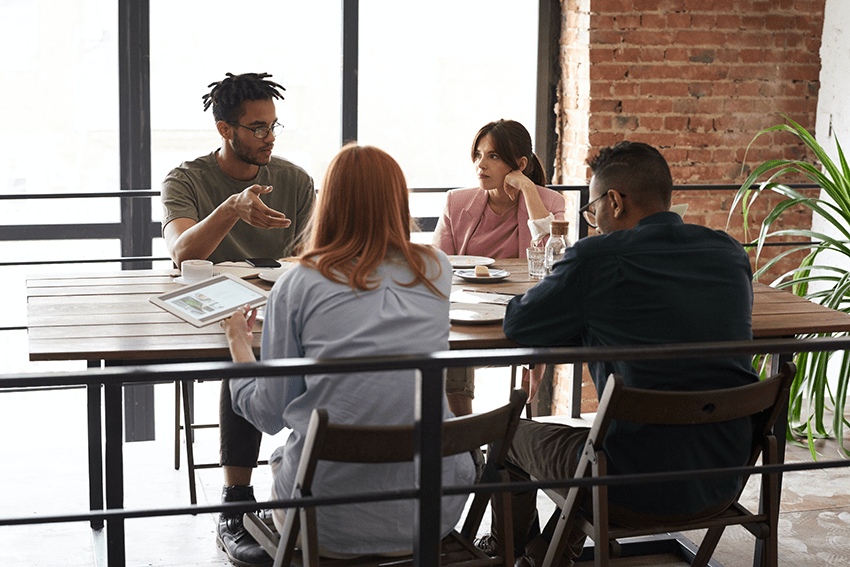 Four people sit at a table talking